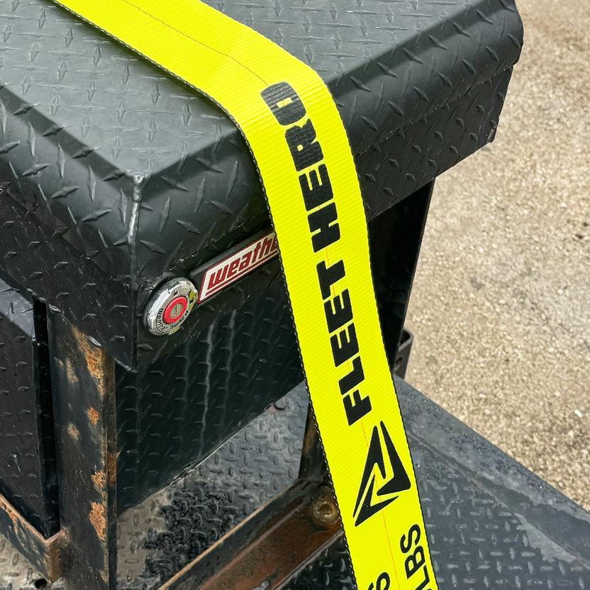 Black toolbox with a yellow 'Fleet Hero' strap on a concrete surface