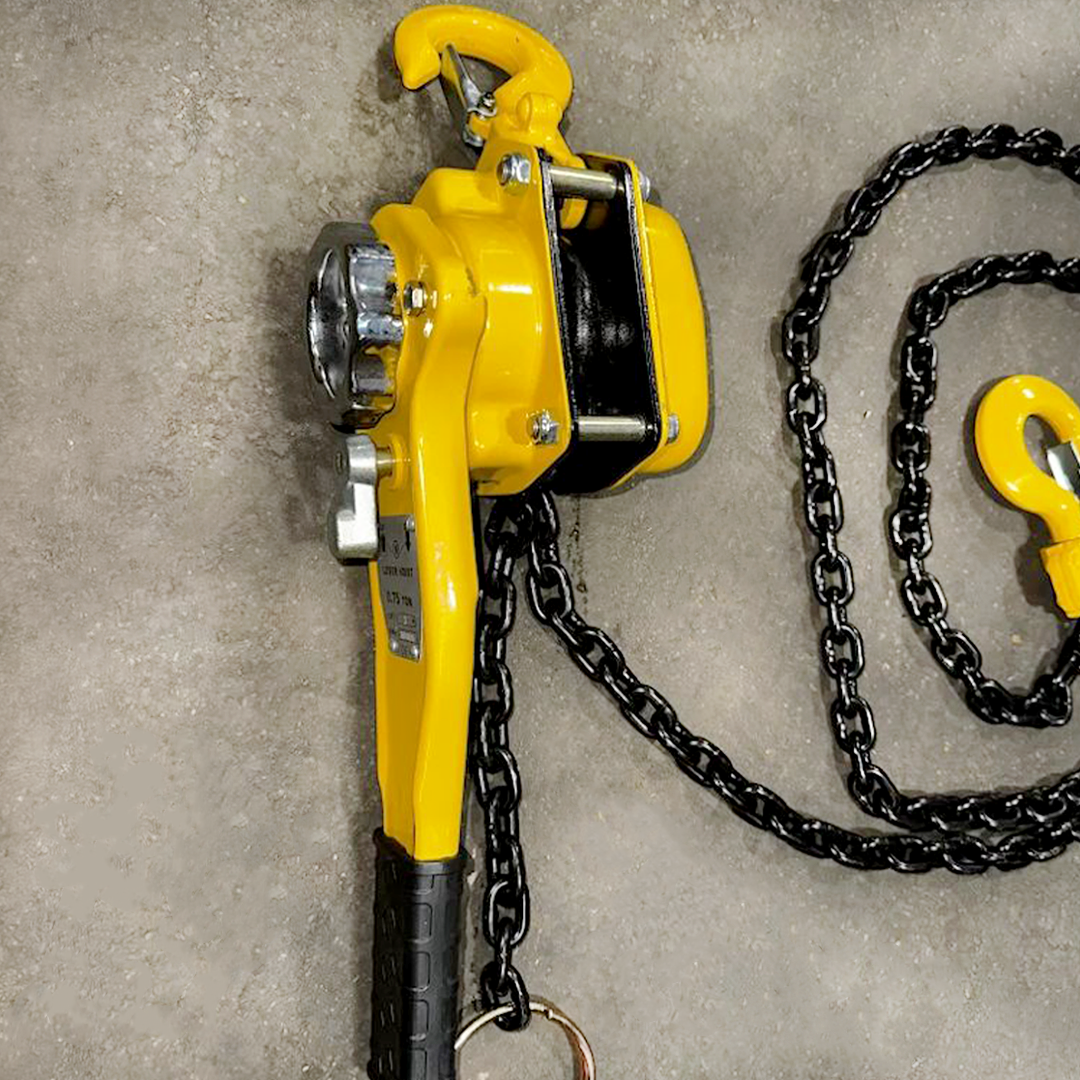 Yellow chain hoist with black chain on a concrete floor