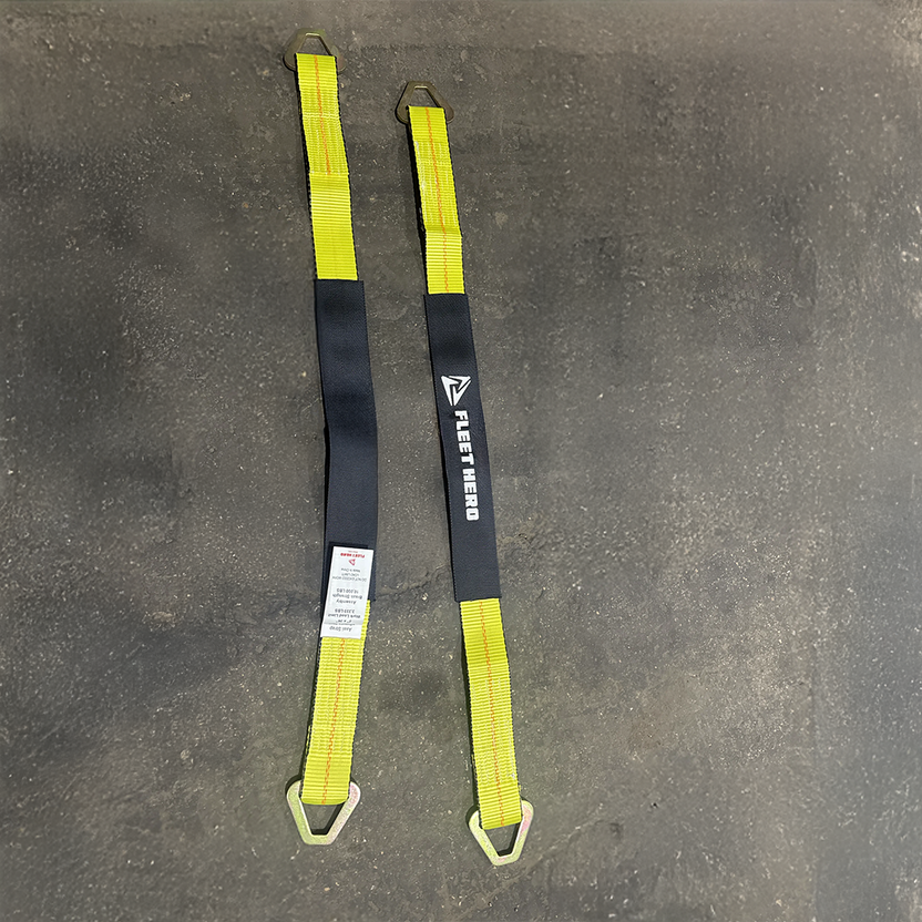 Two yellow and black D-Ring webbing carabiner straps laid flat on a gray concrete floor, with the brand name 'NESTED' printed on one strap.