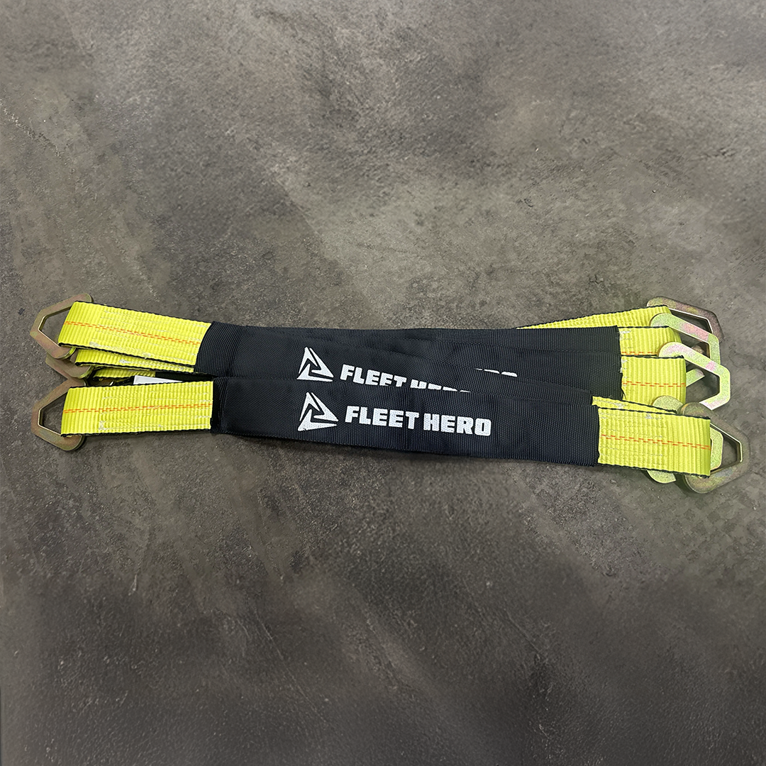 Two black and yellow Fleet Hero strap assemblies with metal buckles, laid flat on a gray concrete floor.